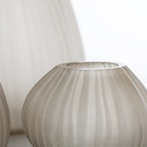 Exquisite Guaxs glass vase in ethereal frosted white, showcasing the brand's mastery of texture and form. The vase's delicate ribbed pattern creates a play of light and shadow, embodying Guaxs' commitment to timeless elegance. Hand-blown by master artisans, this piece exemplifies the fusion of traditional craftsmanship and contemporary design that defines Guaxs' luxurious glass objects.