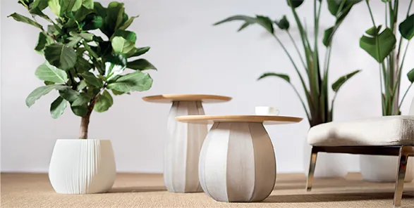 Elegant GUAXS interior setting featuring sleek, organic-shaped planters and side tables. The white ribbed planters house lush green plants, while the tables showcase exquisite glass bases with wooden tops. This composition exemplifies GUAXS' commitment to crafting high-quality, nature-inspired pieces that blend seamlessly with modern interiors, creating a harmonious and sophisticated ambiance.