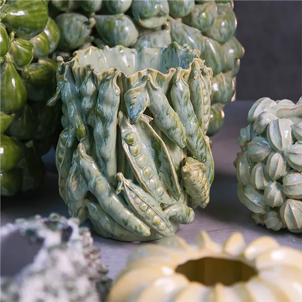 A captivating Des Pots vase showcases the Dutch brand's mastery of whimsical ceramics. This handcrafted piece features an intricate design of lifelike pea pods in varying shades of verdant green. The tactile, organic forms exemplify Des Pots' commitment to creating unique, eye-catching home decor since 1989. Each pod is meticulously sculpted, demonstrating the brand's dedication to artisanal excellence and its signature style of transforming everyday objects into extraordinary art pieces. This vase stands as a testament to Dutch craftsmanship and Des Pots' ability to infuse homes with character and conversation-starting beauty.