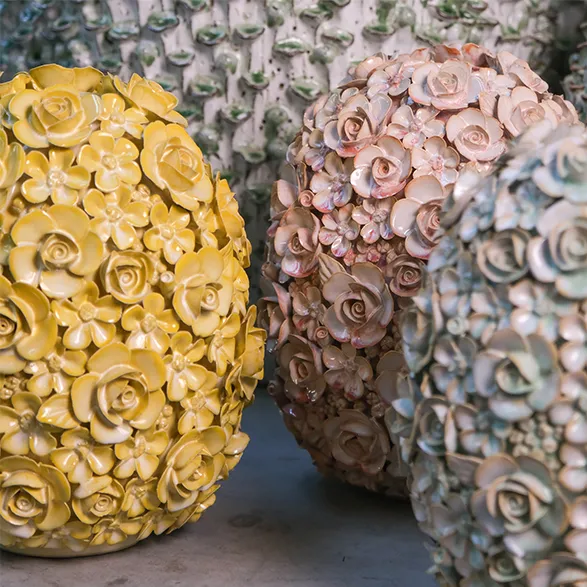 Exquisite Des Pots vases showcase the Dutch brand's mastery of handcrafted ceramics. Each piece is adorned with a profusion of delicate, hand-formed roses in captivating hues of sunny yellow, soft blush, and calming blue-grey. These unique creations exemplify Des Pots' commitment to artisanal excellence since 1989, transforming functional objects into stunning works of art. The intricate floral designs and varied color palette demonstrate the brand's signature style, making each vase a true conversation piece and a testament to Dutch craftsmanship.