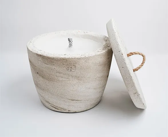 An exquisite concrete candle by Mon Dada, a Belgian brand renowned for its artisanal craftsmanship and minimalist design. The candle is housed in a beautifully textured, natural-toned concrete pot with a rustic lid featuring a rope handle. Mon Dada candles are crafted with high-quality, eco-friendly soy wax, ensuring a clean and long-lasting burn. This piece perfectly embodies the brand's dedication to elegance and sustainability.