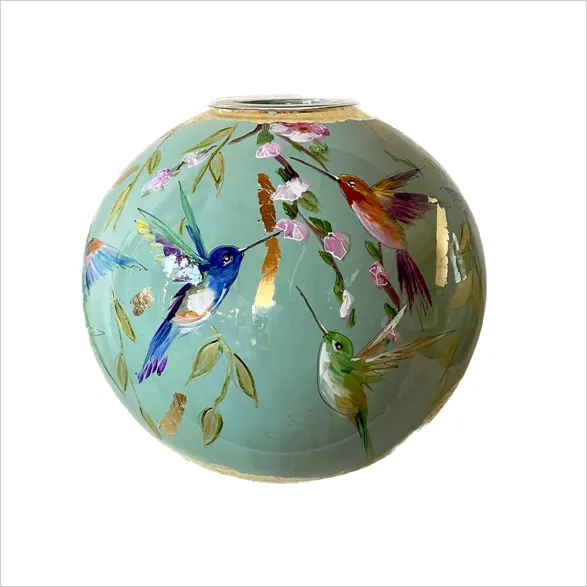 Exquisite hand-painted glass vase 'Pistache' by renowned Dutch artist Doortje IJpellar. This spherical masterpiece features a serene pistachio green background adorned with vibrant hummingbirds and delicate floral motifs. Golden accents highlight the rim and intricate details. A limited edition piece, signed by the artist and crafted in her Netherlands studio, accompanied by a certificate of authenticity.